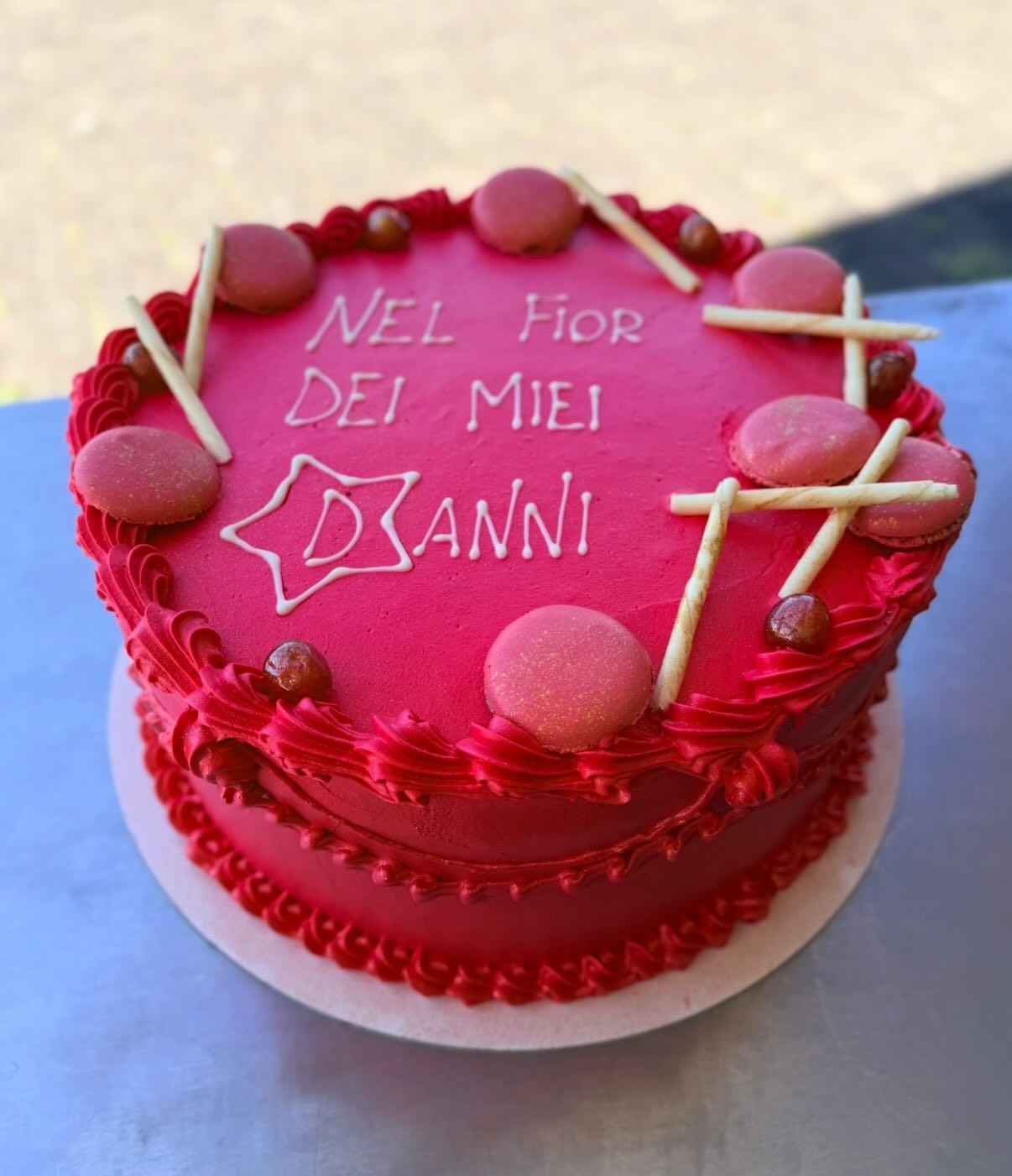 Torta di compleanno decorata con macaron e scaglie di cioccolato